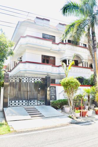 biały budynek z bramą i palmami w obiekcie Madhuraj Hotels w mieście Noida