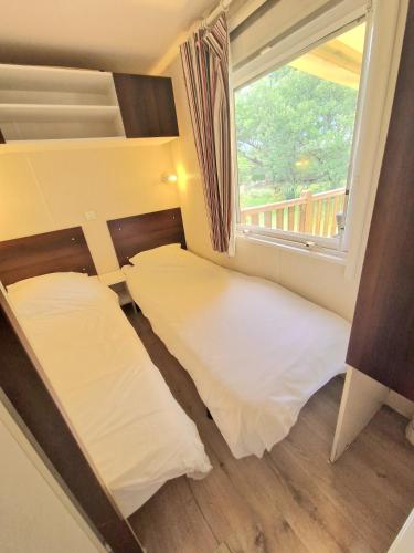 deux lits dans une petite pièce avec une fenêtre dans l'établissement Mobilhome Labenne Océan, à Labenne