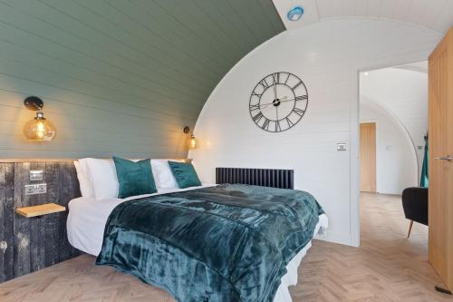 1 dormitorio con 1 cama y reloj en la pared en Choller Lodges - The Barn House With Hot Tub en Arundel