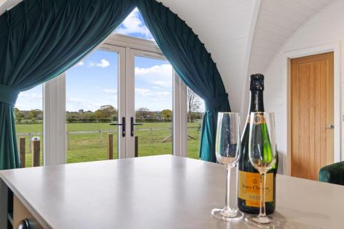 a bottle of wine and two glasses on a counter at Nestledstays - The Barn House With Hot Tub in Arundel