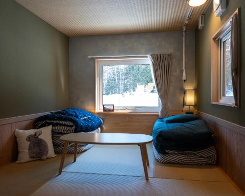 美瑛町にあるC HOTEL 美瑛白金 - Biei Shiroganeのテーブルと窓が備わる小さな客室です。