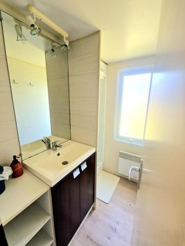 une salle de bain avec un lavabo et un miroir dans l'établissement Mobilhome Labenne Océan, à Labenne