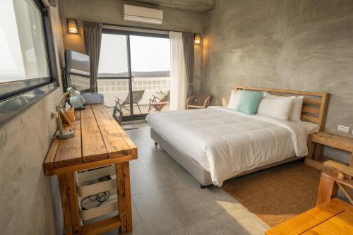 1 dormitorio con cama, mesa y ventana en Serendipity House澎湖望安島, en Wang-an