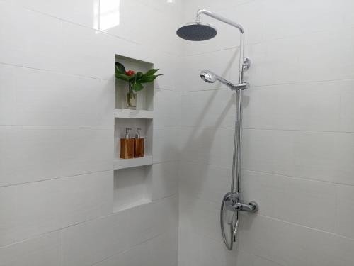 eine Dusche im Bad mit weißen Fliesen in der Unterkunft Manda Homestay in Sanur