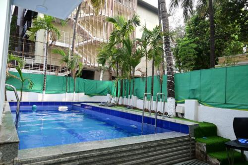 a swimming pool in front of a building with palm trees at Blue Pearl A Boutique Hotel in Goa