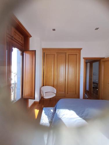 a bedroom with a bed and a chair and a window at Casa Mama in Vigo