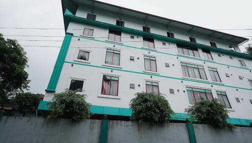 a white building with red windows on top of a wall at Hotel O Greenland in Meppādi