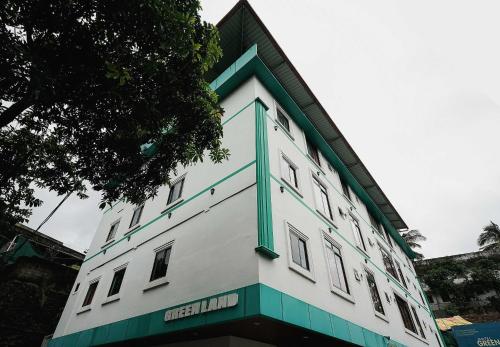 a white building with a green trim at Hotel O Greenland in Meppādi