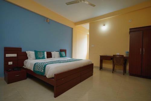 a bedroom with a large bed and a desk at Hotel O Greenland in Meppādi
