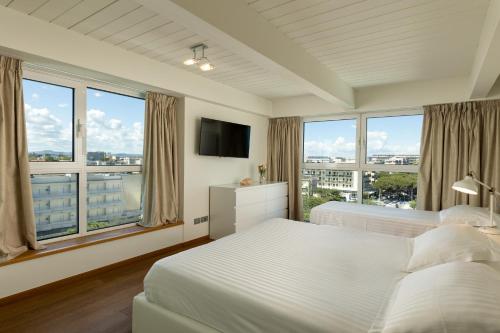 a bedroom with two beds and a tv and windows at Artis Appartamento in Rimini