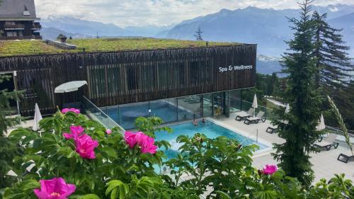 um edifício com uma piscina com montanhas ao fundo em Les Cerfs - Appartement & Studio - ANZERE em Anzère