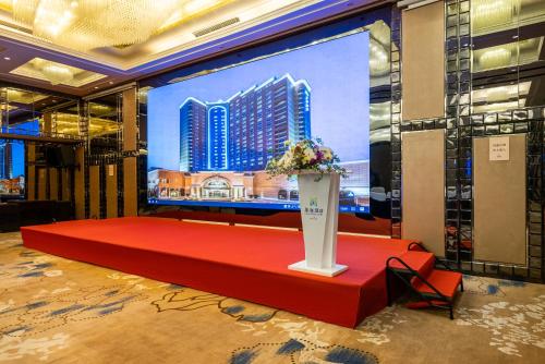 GuangDong Hotel Shanghai في شانغهاي: شاشة كبيرة مع طاولة حمراء عليها زهور