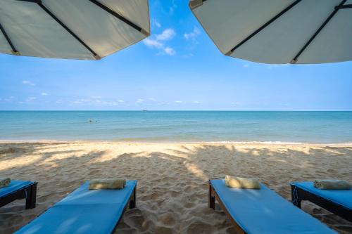two blue benches on a beach with the ocean at Anja Beach Resort & Spa in Phu Quoc