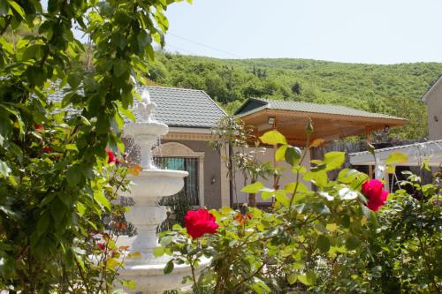 uma grande fonte branca num jardim com rosas em Museum Guest House-Muzey Ailəvi Qonaq Evi em Sheki