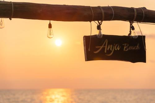 a sign on a pole with the ocean in the background at Anja Beach Resort & Spa in Phu Quoc