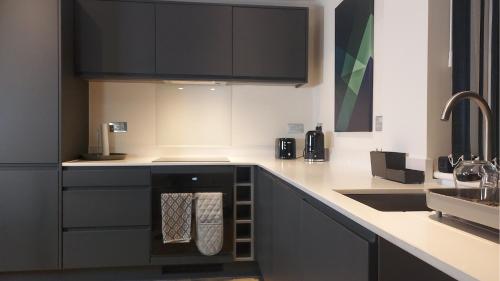 a kitchen with black cabinets and a sink at Stunning one bedroom near Old Trafford Stadium in Manchester