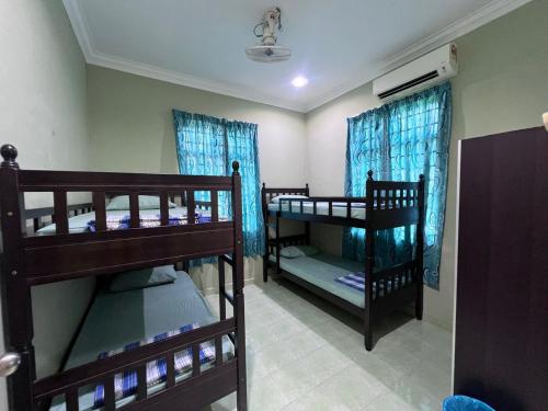 a room with three bunk beds with blue curtains at Muhibbah Homestay 1 in Port Dickson