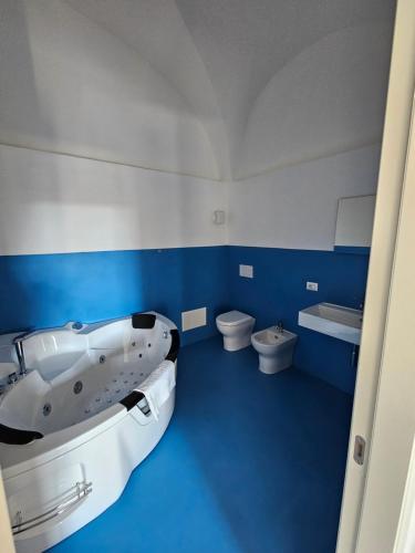 a blue and white bathroom with a tub and toilet at La Dama del Castello in Bosa