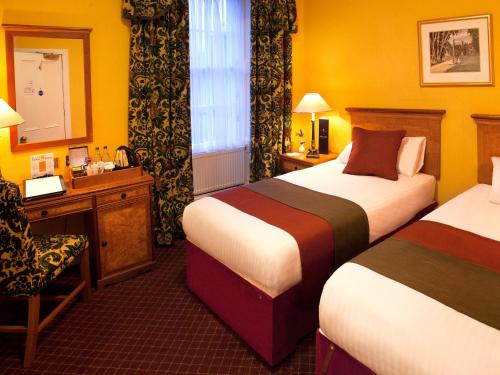 um quarto de hotel com duas camas e uma cadeira em The Royal Highland Hotel em Inverness