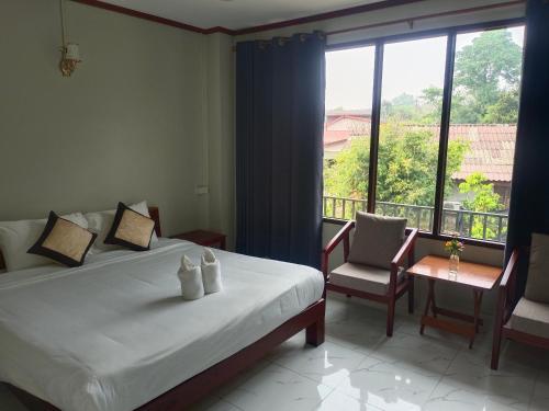 a bedroom with a bed and a large window at Vang Vieng Champa Hotel in Vang Vieng