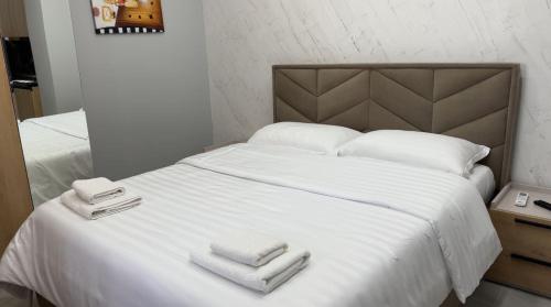 Una cama blanca con dos toallas encima. en Albania Dream Holidays Studios, en Sarandë