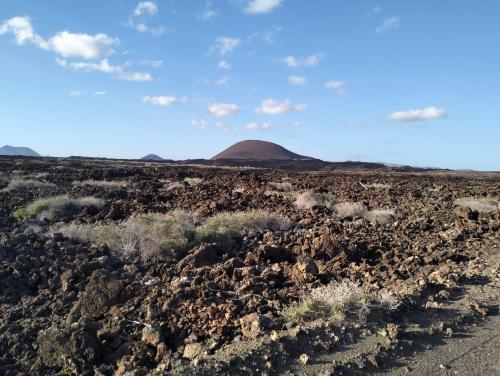 a lava field with ayers rock in the background at Casa rural Daisamar in Teguitar