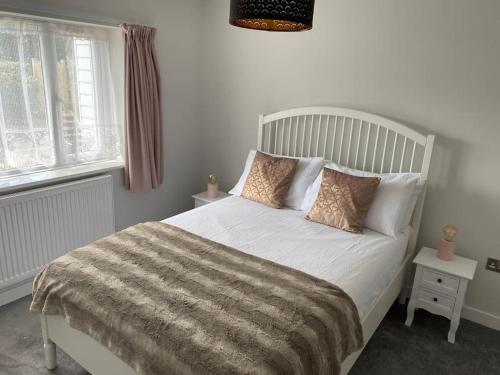 um quarto com uma cama branca e 2 janelas em Seabreeze -modern spacious house with great garden em Lyme Regis