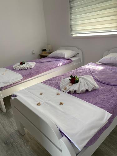 three beds in a room with purple and white sheets at Apartman Pranić Mostar in Mostar