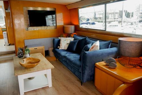 a living room with a blue couch and a table at Yacht Aquamarina vieux port La Rochelle in La Rochelle