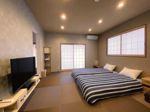 a bedroom with a large bed and a flat screen tv at My Home Inn Izumisano in Izumi-Sano