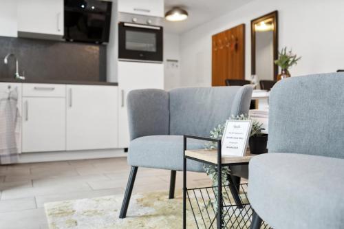 a living room with chairs and a table and a kitchen at Amelie chez Inez in Radolfzell am Bodensee