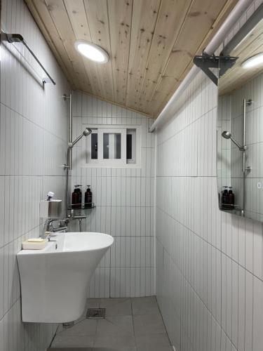 La salle de bains blanche est pourvue d'un lavabo et d'une douche. dans l'établissement 한옥스테이 오늘 Hanok Stay Ohneul, à Gyeongju