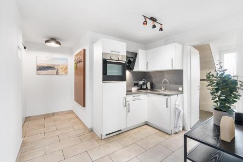 a kitchen with white cabinets and a table at Amelie chez Inez in Radolfzell am Bodensee