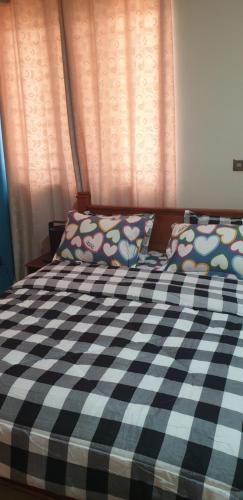 a bed with a black and white checkered blanket and pillows at the Oxbow in Madina