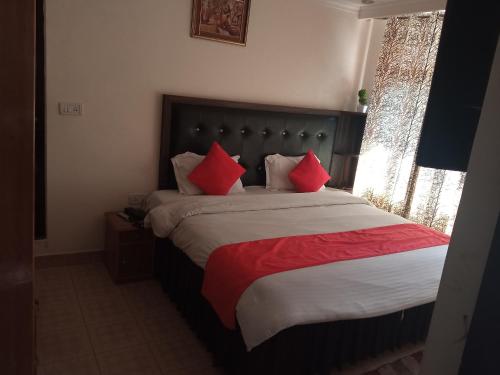 a bedroom with a large bed with red pillows at Mountain in Dharamshala