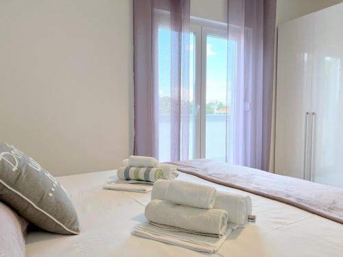 a bedroom with two towels on a bed with a window at Evergreen & Pinky Apartments close to the Beach in Rab