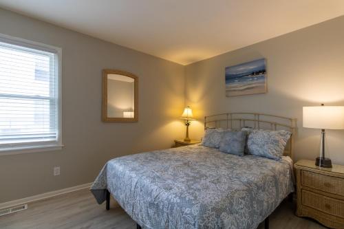 een slaapkamer met een bed, een lamp en een raam bij Cozy 3BR Home - Steps from the Shore in Brigantine