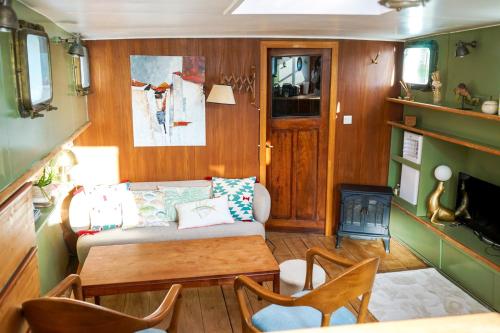 a living room with a couch and a table and a stove at UNE PENICHE DANS LE BASSIN À FLOT DU VIEUX PORT in La Rochelle