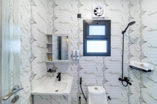 a white bathroom with a sink and a mirror at جوهرة مسقط للشقق الفندقية in Ma‘ābīlah