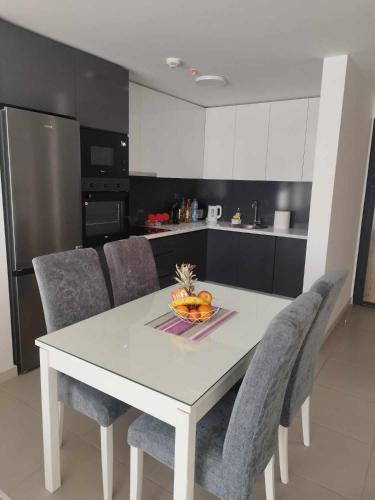 a kitchen with a white table and chairs with a bowl of fruit at Skopje Sky Apartments & Floor 33th 28th & 25th & 19th & 13th 12th With Pool & Spa & Fitness & Parking Included in Price in Skopje
