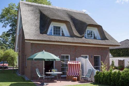 a house with a thatched roof with a table and chairs at Reethus Natalie in Zingst