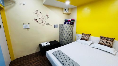ein Schlafzimmer mit einem Bett und einer gelben Wand in der Unterkunft The Little Peaceful Cozy Home ! Aadhish Homestay in Varanasi
