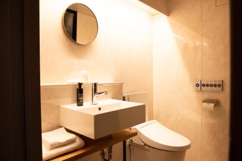 a bathroom with a sink and a toilet and a mirror at Ryokan Asakusa Shigetsu in Tokyo
