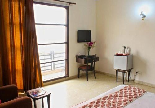 a living room with a large window and a television at Hotel Jashn Inn near Apollo Hospital in New Delhi