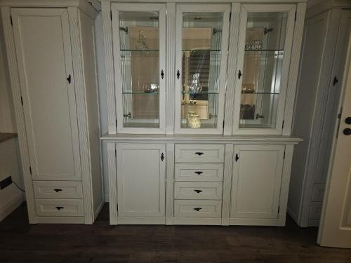 a white hutch with glass doors and drawers at Ferienwohnung Grimma in Grimma