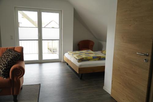 um quarto com uma cama, uma cadeira e uma janela em Ferienwohnung Thulbatal em Oberthulba