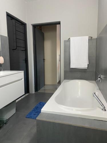 ein Badezimmer mit einer großen weißen Badewanne und einem Waschbecken in der Unterkunft SeaBreeze Guest Suite in Kapstadt