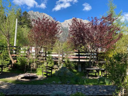 a park with picnic tables and trees with mountains in the background at Apartament Pensiunea Liziera in Buşteni
