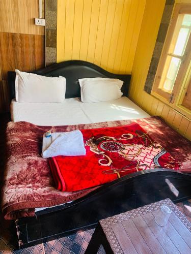 a bedroom with a bed with a red blanket at The Gurez inn hotel and restaurant in Kanzalwan