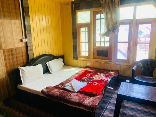 a bedroom with a bed with a red blanket on it at The Gurez inn hotel and restaurant in Kanzalwan